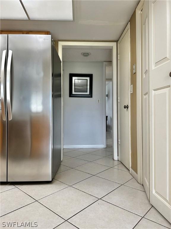 kitchen with light tile patterned floors and stainless steel refrigerator