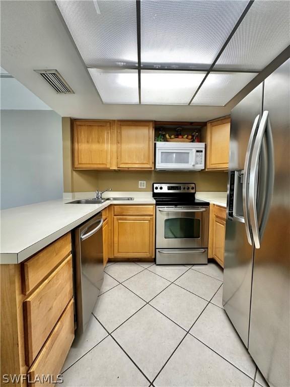 kitchen featuring kitchen peninsula, sink, light tile patterned floors, and stainless steel appliances