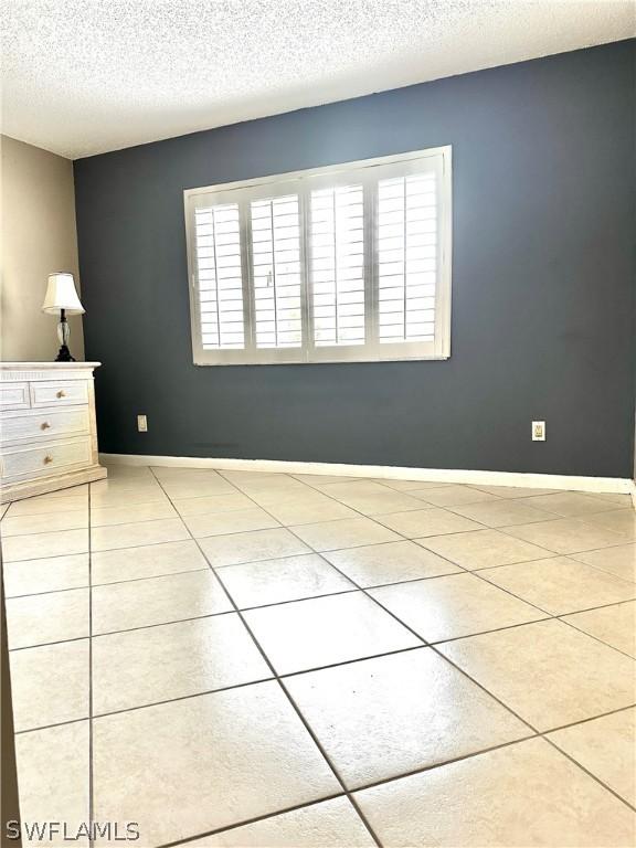 empty room with light tile patterned flooring and a textured ceiling