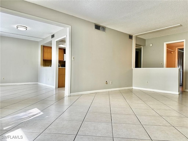 empty room with light tile patterned flooring and a textured ceiling