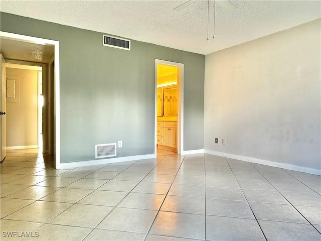 tiled empty room featuring ceiling fan and a textured ceiling