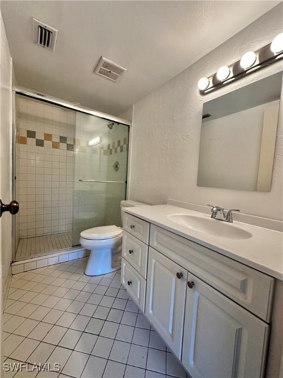 bathroom featuring tile patterned floors, vanity, walk in shower, and toilet