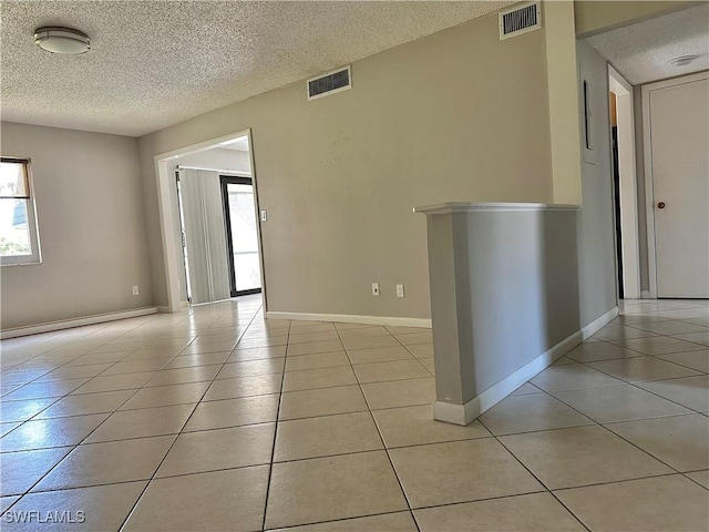 spare room with visible vents, baseboards, a textured ceiling, and light tile patterned flooring