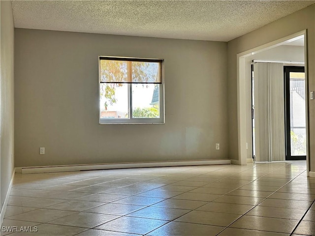 tiled empty room with a baseboard radiator, baseboards, and a textured ceiling