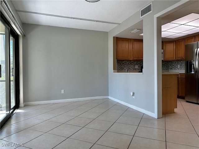 unfurnished room with light tile patterned flooring, baseboards, visible vents, and a wealth of natural light