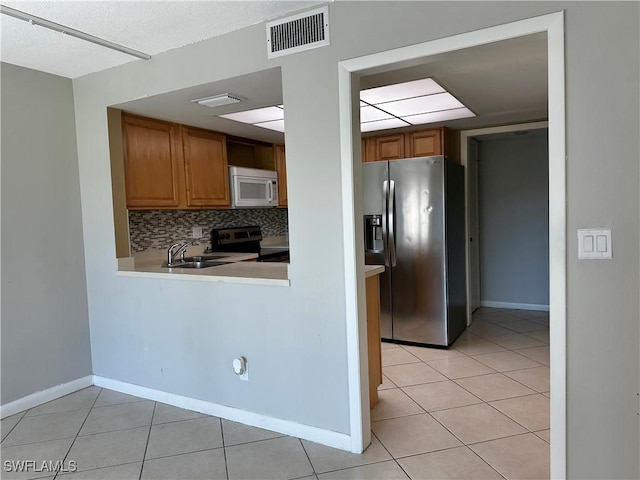 kitchen with tasteful backsplash, visible vents, light countertops, light tile patterned floors, and stainless steel appliances