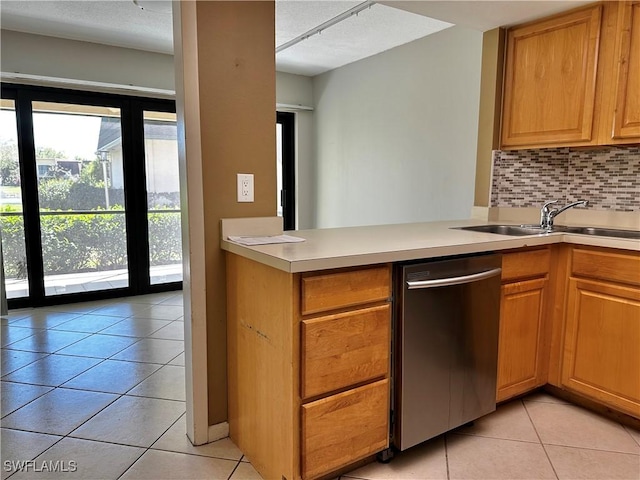 kitchen with tasteful backsplash, light countertops, stainless steel dishwasher, light tile patterned flooring, and a sink