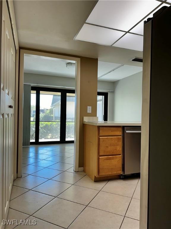 kitchen featuring light tile patterned floors, brown cabinetry, light countertops, and visible vents