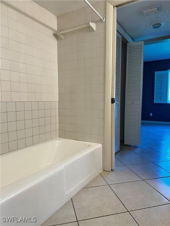 bathroom with tile patterned floors, visible vents, and shower / washtub combination