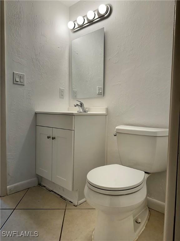 bathroom featuring vanity, toilet, a textured wall, and tile patterned flooring