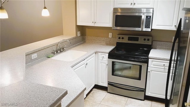 kitchen featuring appliances with stainless steel finishes, decorative light fixtures, sink, and white cabinets