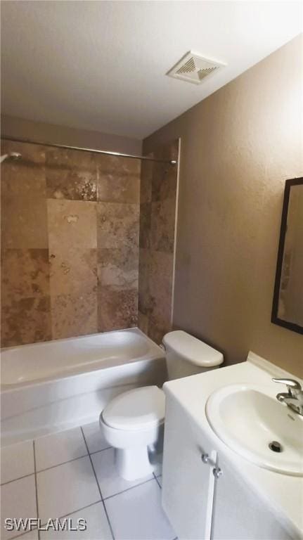 full bathroom with tile patterned flooring, vanity, tiled shower / bath, and toilet