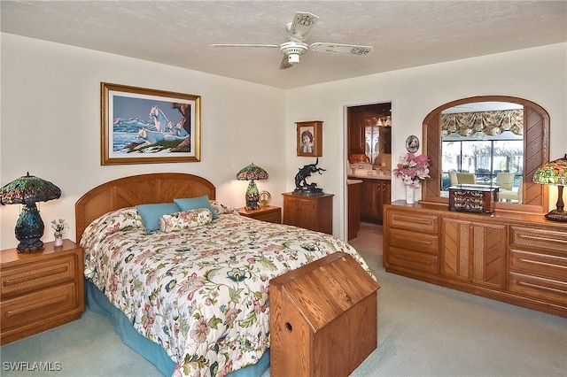 carpeted bedroom featuring ensuite bathroom, ceiling fan, and a textured ceiling