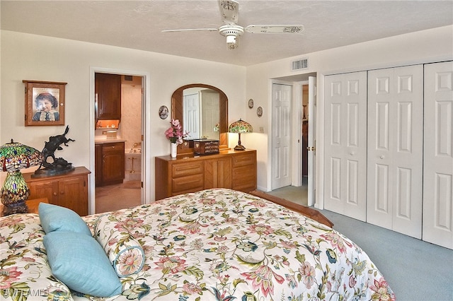 carpeted bedroom featuring ceiling fan, ensuite bathroom, and a textured ceiling