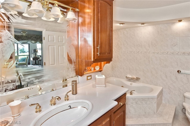 bathroom with vanity, toilet, and tiled bath