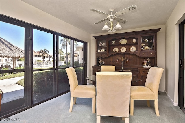 carpeted dining area with ceiling fan and wood walls