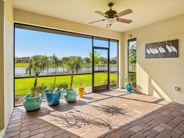 unfurnished sunroom featuring a water view and ceiling fan