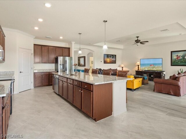 kitchen featuring appliances with stainless steel finishes, ceiling fan, decorative light fixtures, a center island with sink, and sink