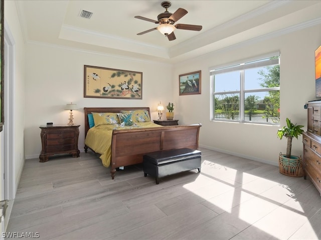 bedroom featuring ceiling fan, a raised ceiling, crown molding, and light hardwood / wood-style floors