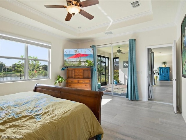 bedroom featuring light wood finished floors, access to outside, visible vents, and a raised ceiling