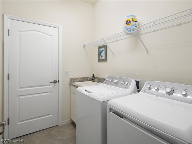 clothes washing area featuring sink, washing machine and clothes dryer, and cabinets