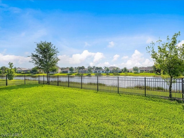 view of yard with a residential view, a water view, and fence