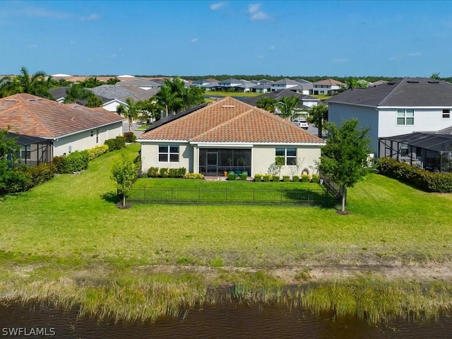 back of property with a residential view, fence, a tiled roof, and a lawn