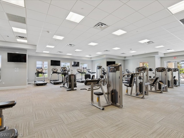 gym featuring light carpet, a drop ceiling, and a healthy amount of sunlight