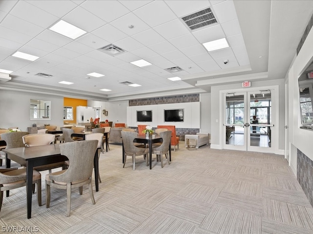 dining area featuring light colored carpet, a tray ceiling, and french doors