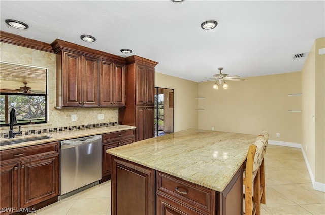 kitchen with light stone countertops, ceiling fan, sink, light tile floors, and stainless steel dishwasher