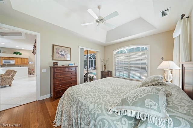 tiled bedroom with ceiling fan, a walk in closet, and a tray ceiling