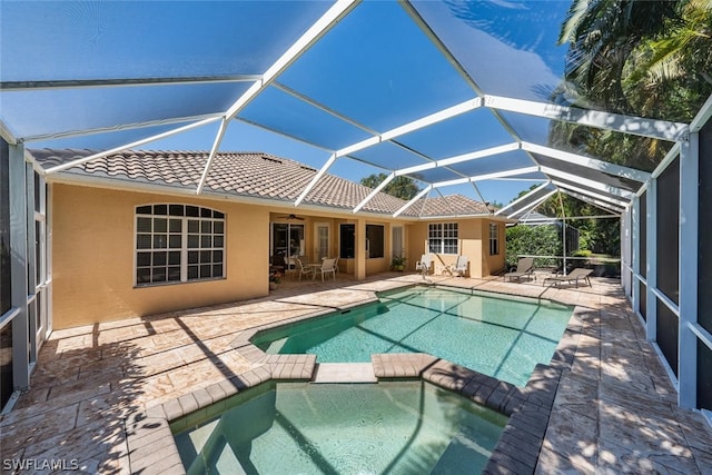 view of pool with a patio, glass enclosure, and an in ground hot tub