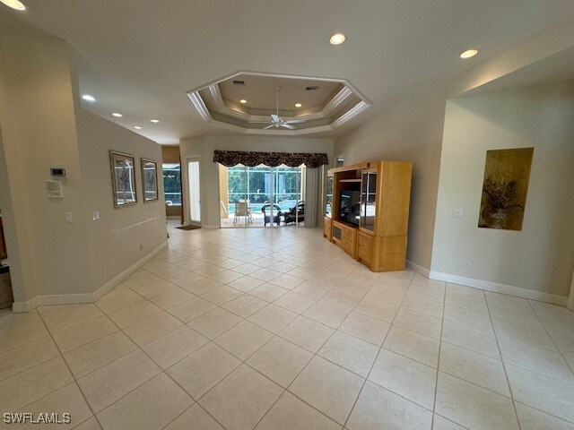 interior space featuring a raised ceiling, ceiling fan, and light tile patterned floors