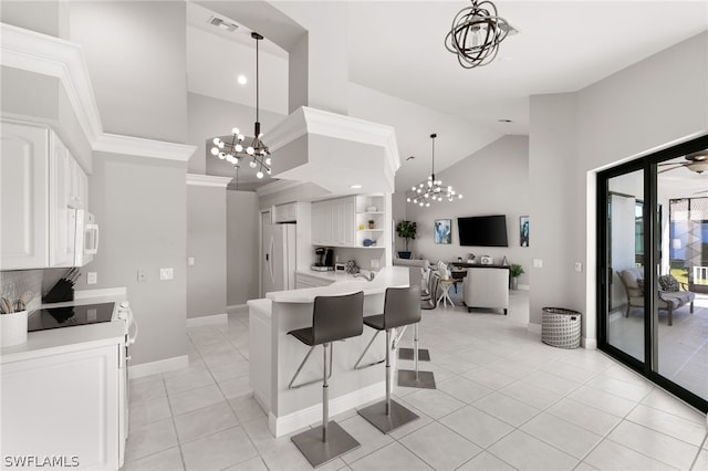 kitchen with white cabinets, hanging light fixtures, light tile flooring, and high vaulted ceiling