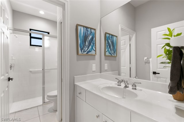 bathroom with vanity with extensive cabinet space, a shower with shower door, toilet, and tile flooring