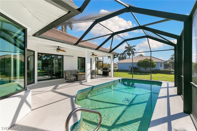 view of pool featuring glass enclosure, ceiling fan, grilling area, a lawn, and a patio area