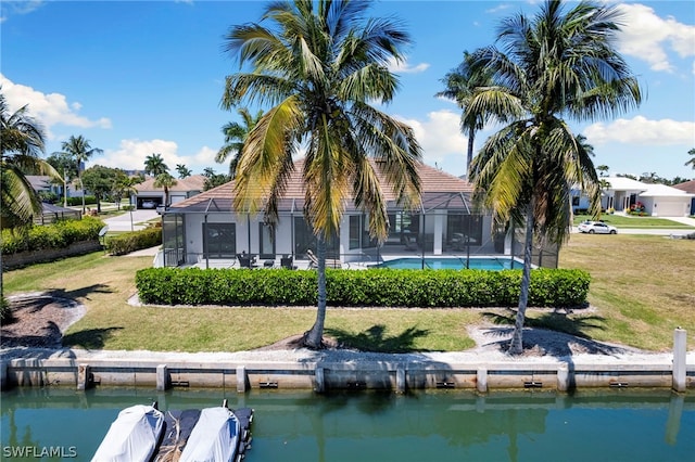 back of house with a water view, a yard, and a lanai