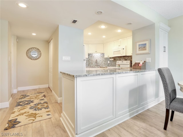 kitchen with light hardwood / wood-style floors, light stone countertops, white appliances, white cabinets, and backsplash