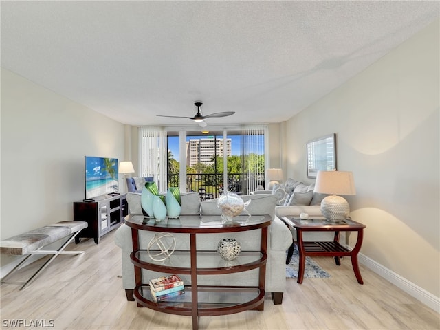 living room featuring ceiling fan, a textured ceiling, and light wood-type flooring