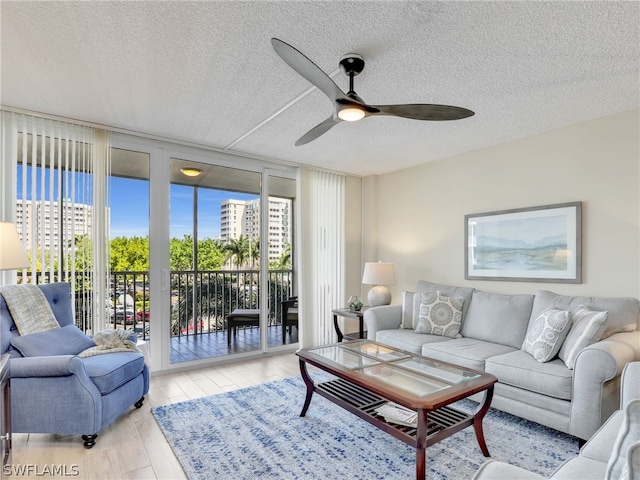 living room featuring light hardwood / wood-style floors, a textured ceiling, and ceiling fan