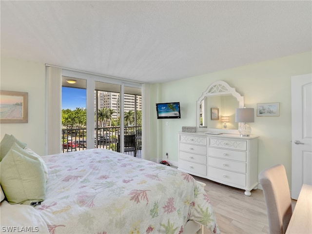 bedroom featuring access to exterior, light hardwood / wood-style floors, and a textured ceiling