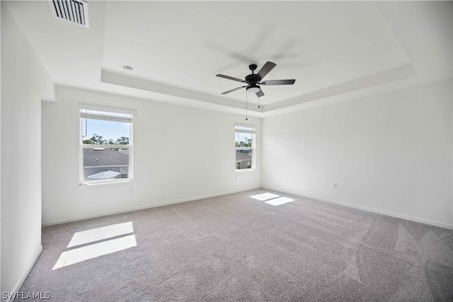 unfurnished room with a raised ceiling, ceiling fan, and carpet floors