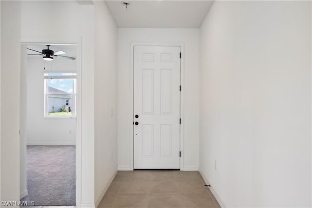 entryway with ceiling fan and light carpet