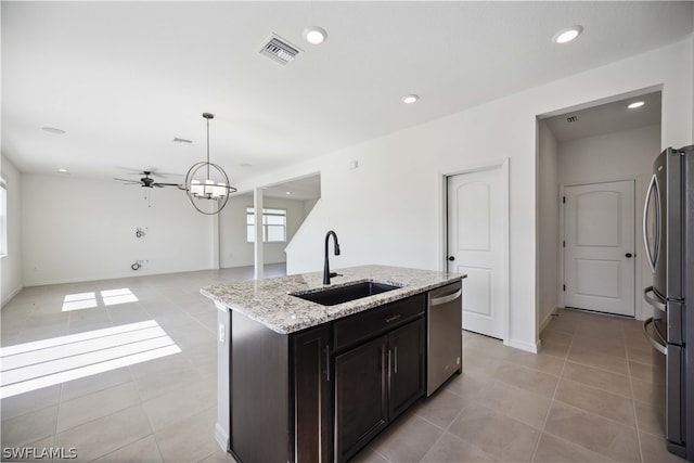 kitchen with an island with sink, appliances with stainless steel finishes, decorative light fixtures, ceiling fan with notable chandelier, and sink