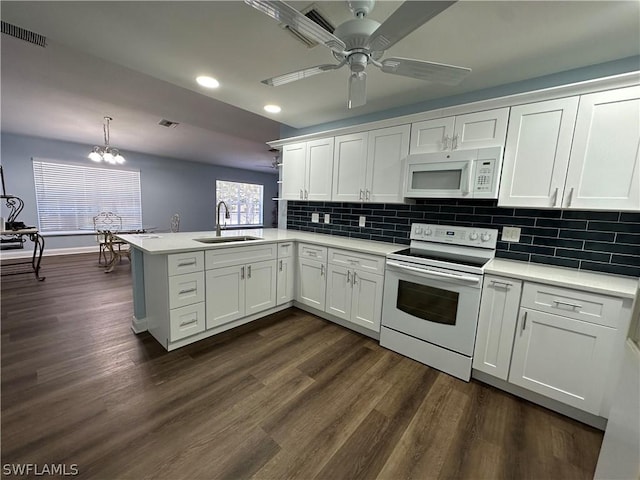 kitchen with visible vents, white cabinets, a sink, white appliances, and a peninsula