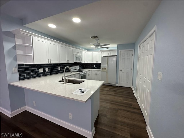 kitchen featuring visible vents, light countertops, a sink, white appliances, and a peninsula