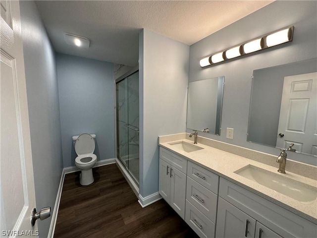 bathroom featuring toilet, a stall shower, a sink, and wood finished floors