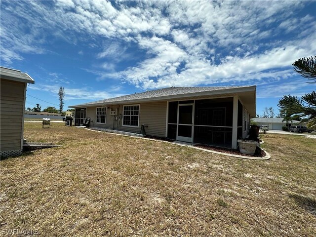 back of property with a yard and a sunroom