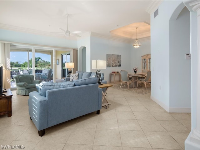 tiled living room with a raised ceiling and ceiling fan with notable chandelier