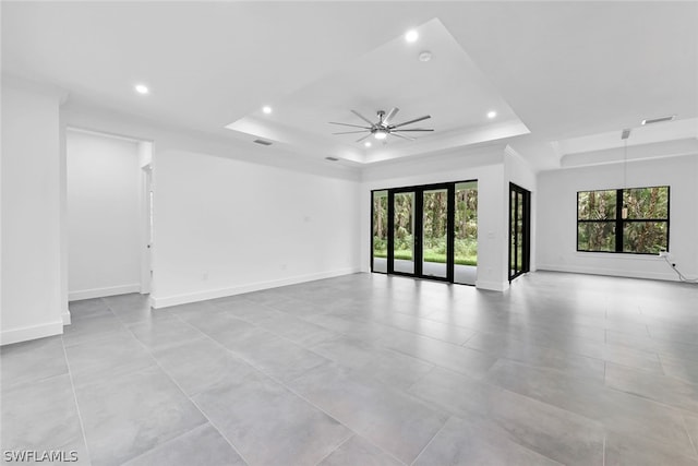 tiled spare room with a tray ceiling and ceiling fan